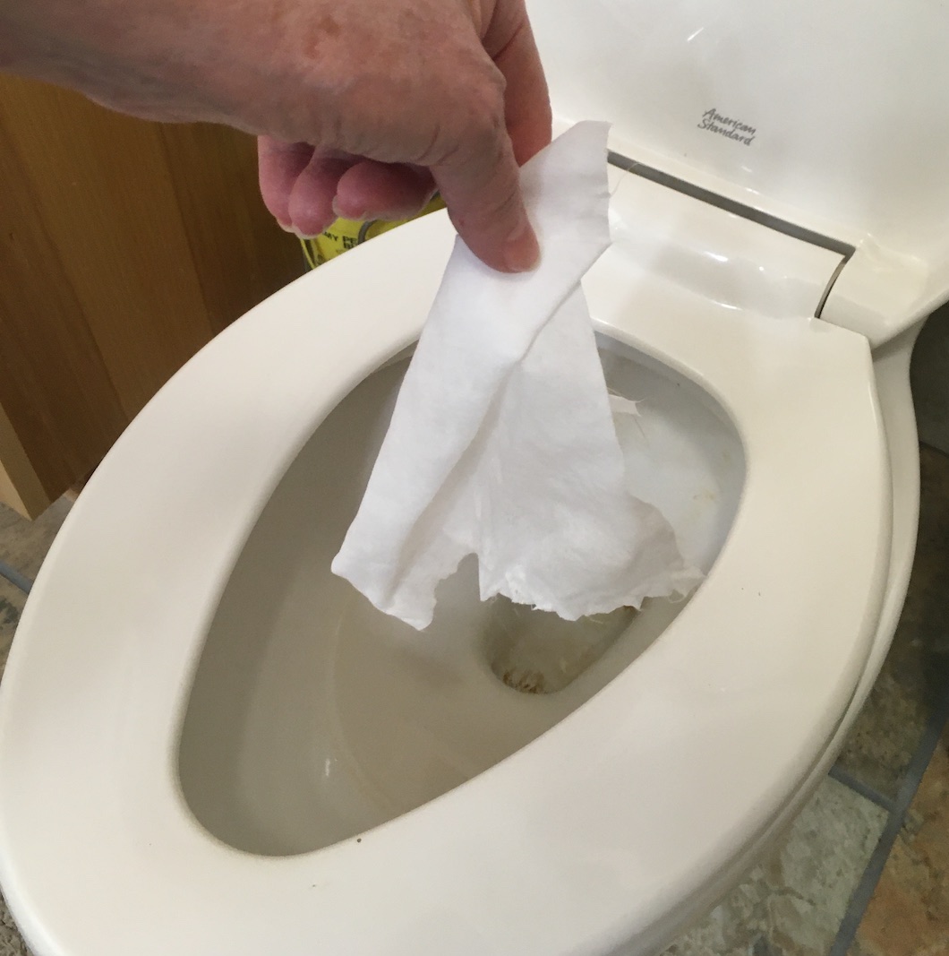 A hand flushing an antibacterial wipe.