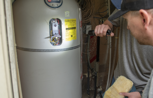 Petersen Plumbing examining a customer's water heater.
